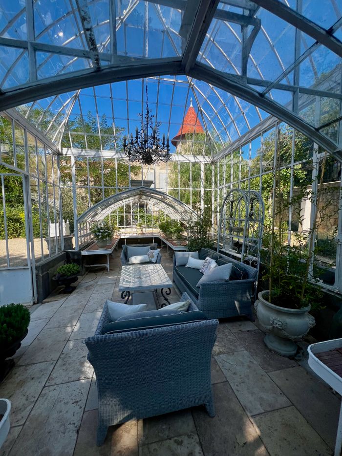 Luxurious glass conservatory with vintage decor and a stunning chandelier.